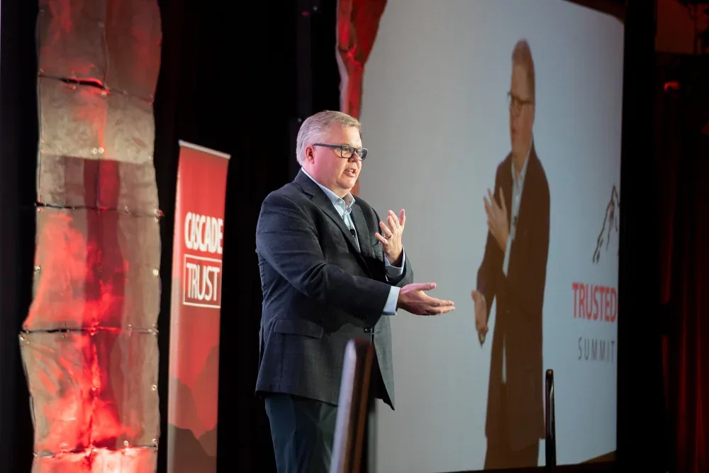 Speaker presenting on stage at a trusted leadership summit.